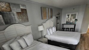 Quarto com duas camas, mesa de cabeceira com abajur, cômoda e espelho.