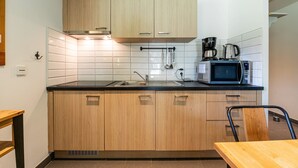 Een keuken met houten kastjes, een zwart aanrecht, een magnetron, een koffiezetapparaat en een spoelbak.