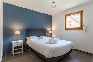 Une chambre à coucher comprenant un lit, des lampes de chevet, une table de chevet, une fenêtre avec vue et un luminaire au plafond.