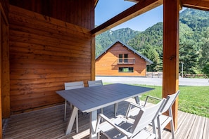 Une cabane en bois dotée d’un balcon, d’une table avec des chaises et offrant une vue sur une montagne.