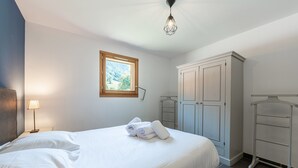 Een slaapkamer met een bed, een raam, een kledingkast en een hanglamp.