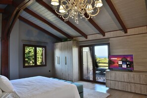 Un dormitorio con cama, televisor, armario, candelabro y vistas a través de una puerta.