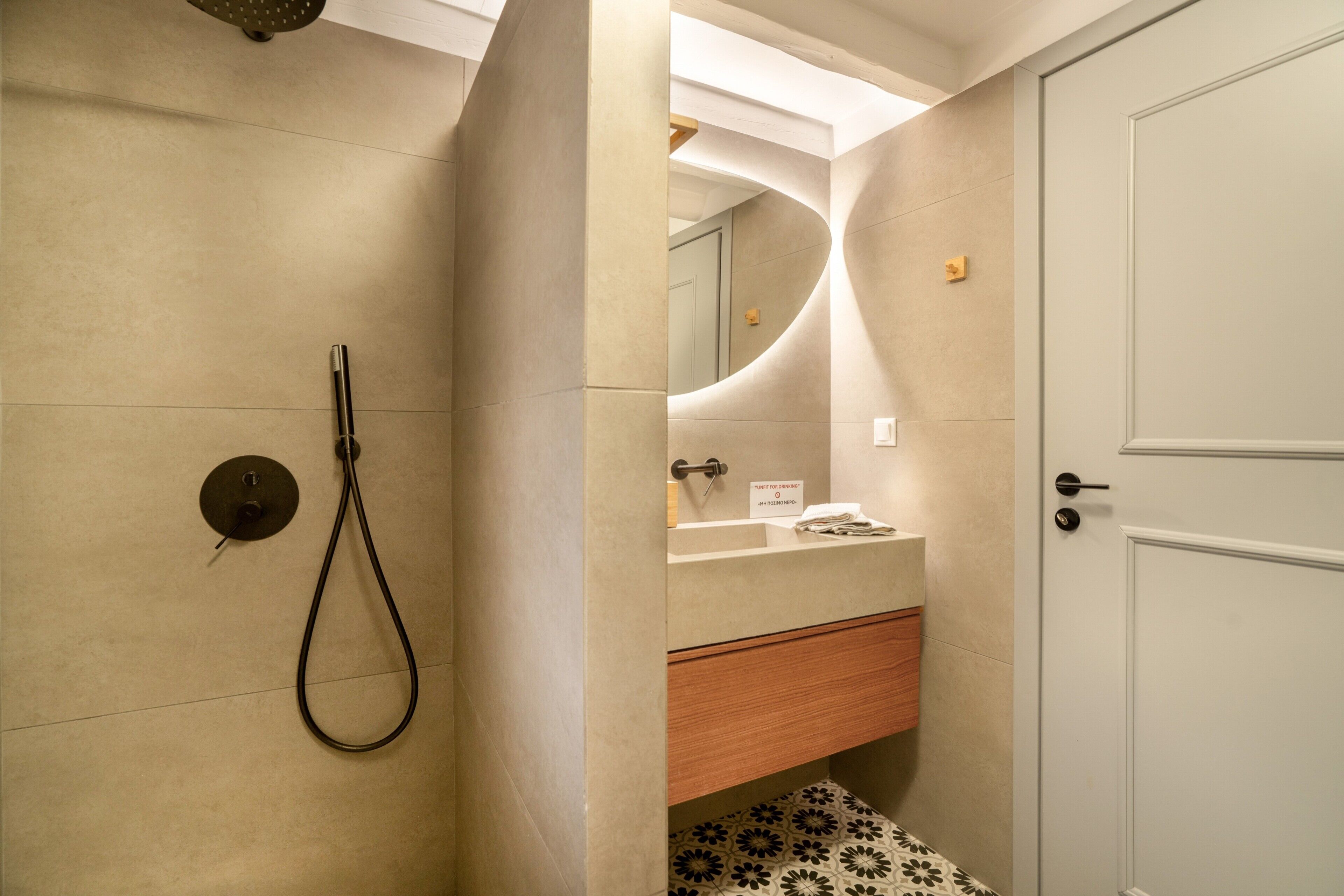 A bathroom with a shower, a sink, a mirror, and a door.