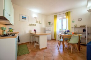 Une cuisine compacte dotée d’un îlot central, d’un petit réfrigérateur et d’un coin repas avec des chaises et une table.