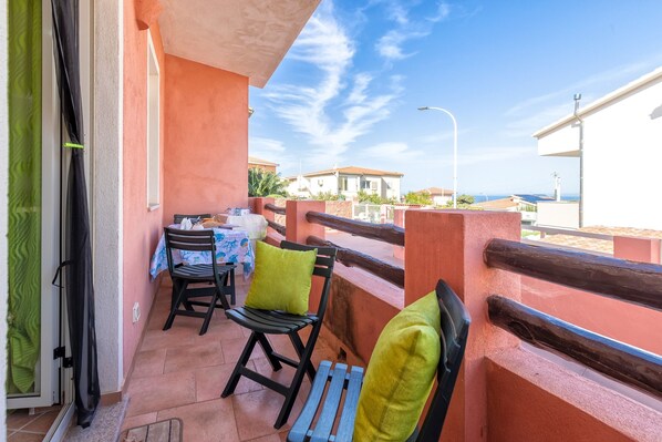 Un balcon avec une table et des chaises, une vue sur la mer et un bâtiment en arrière-plan.