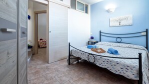 Une chambre à coucher comprenant un lit, une armoire, une fenêtre et un luminaire fixé au mur.