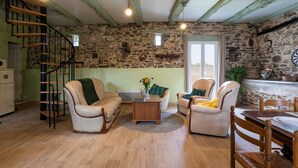 Een gezellige woonkamer met een stenen muur, een houten trap en een eethoek met een tafel en stoelen.