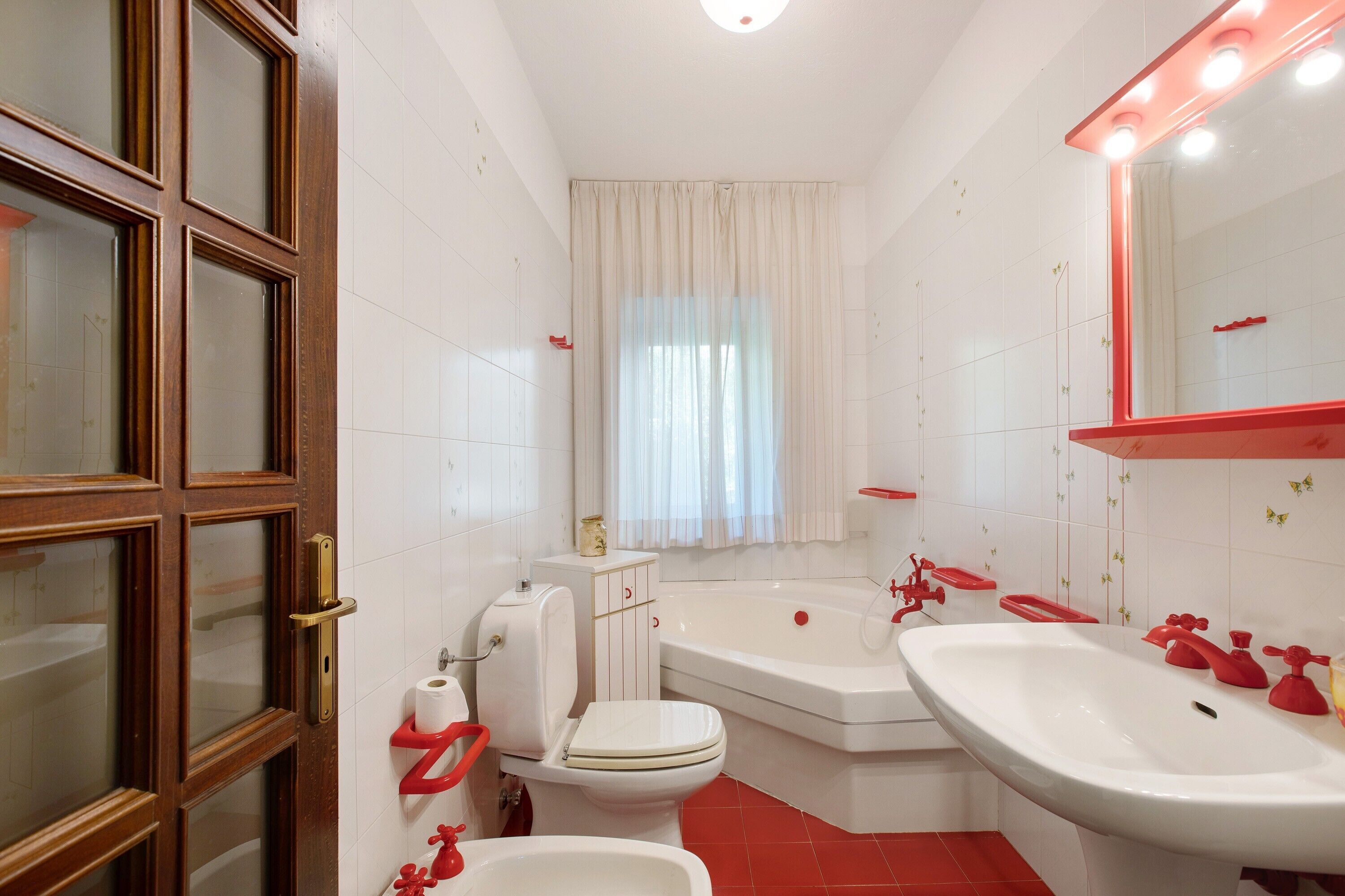Ein Badezimmer mit Toilette, Waschbecken, Badewanne und einem beleuchteten Spiegel.