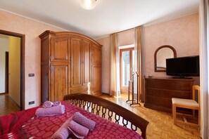 A bedroom with a bed, wooden wardrobe, television, and a chair. - Apartment 'Casa Mauro Con Vista Su Aosta' with Mountain View (Aosta)