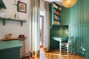Una habitación con mobiliario color turquesa, un escritorio de madera, una silla, un radiador y una estantería.