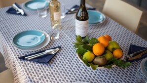 A table set with blue plates, a bottle of white wine, and a bowl of fruit. - Villa 'Sunflower' with Private Garden and Wi-Fi (Capalbio)