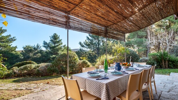 An outdoor dining area with a table set for four, surrounded by chairs, under a bamboo canopy. - Villa 'Sunflower' with Private Garden and Wi-Fi (Capalbio)