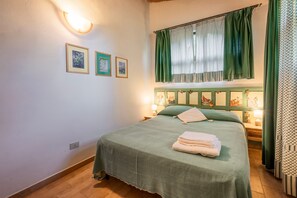 Ein Schlafzimmer mit einem Bett, grünen Vorhängen, Wandleuchten und gerahmten Bildern.