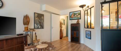 Una sala de estar moderna con un televisor de pantalla plana, muebles de madera y obras de arte en las paredes.