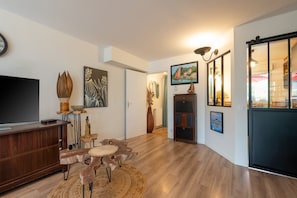 A modern living room with a flat-screen TV, wooden furniture, and artwork on the walls.