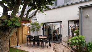 A patio with a table and chairs, a wicker chair, and a wooden fence. - Holiday Home 'Upton 2 - Arradon Golfe Du Morbihan' with Private Terrace, Garden & Wi-Fi (Arradon)