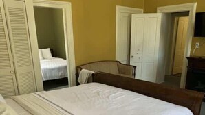 Une chambre à coucher avec un grand lit, une tête de lit en bois et une armoire à portes à persiennes.