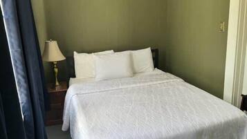 A bedroom with a bed, a nightstand, and a lamp.
