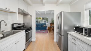 A modern kitchen with white cabinetry, stainless steel appliances, and a wooden floor.