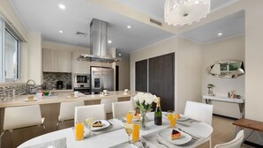 A modern kitchen with a central island, stainless steel appliances, and a dining area with a table set for four. - Eagle Beach Resort Ground Level 3BR2BA Pool Levent (Oranjestad)