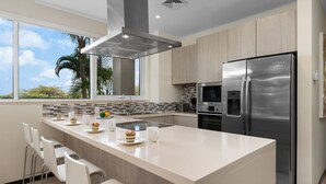 A modern kitchen with a large island, stainless steel appliances, and a view of palm trees. - Eagle Beach Resort Ground Level 3BR2BA Pool Levent (Oranjestad)