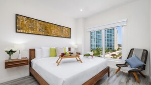 Une chambre d’hôtel moderne avec un grand lit, une table de chevet avec une lampe, une chaise, une fenêtre donnant sur la ville et un élément décoratif mural.