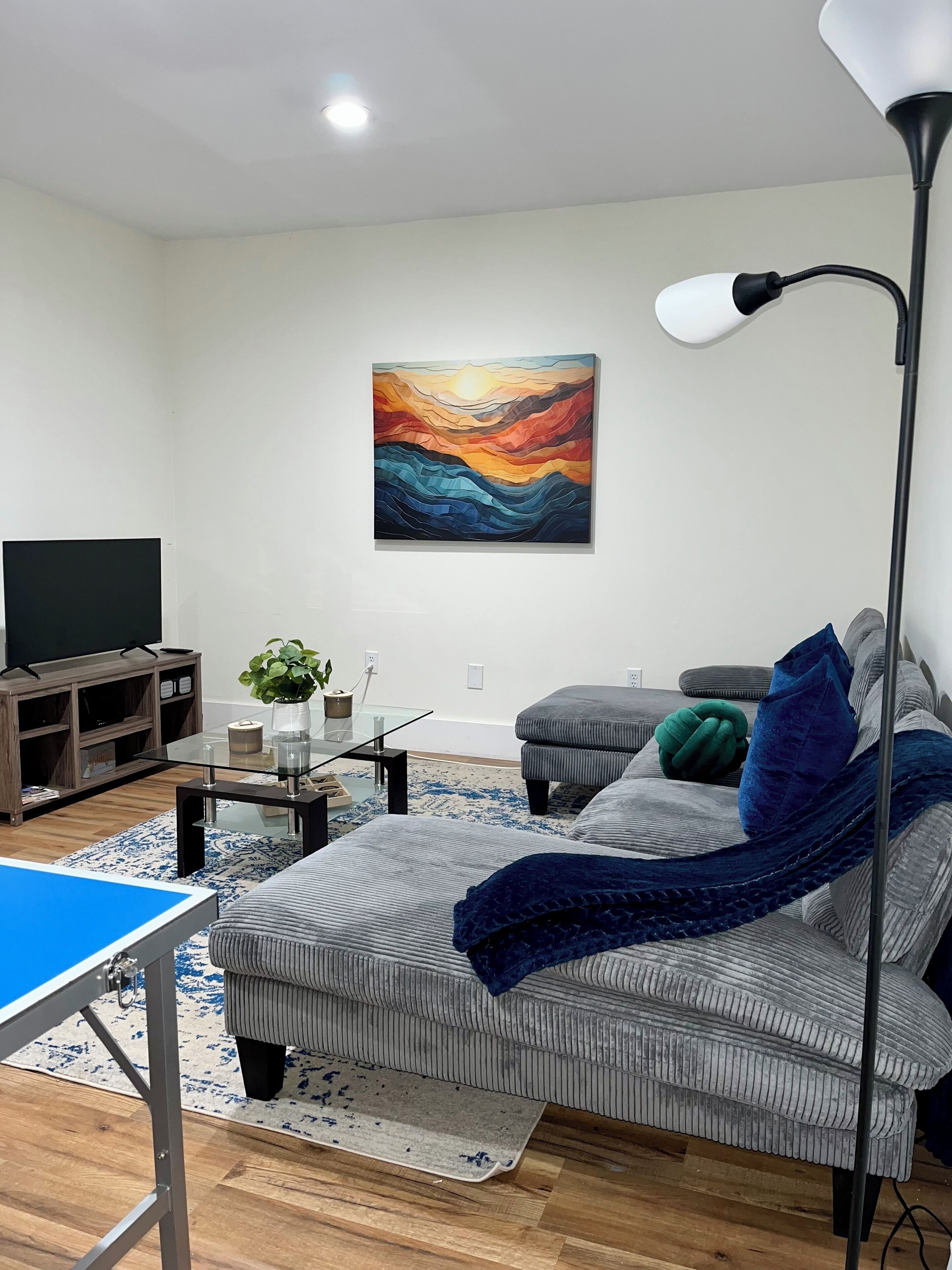 Un salon moderne avec un canapé, une table basse, un téléviseur et un tableau accroché au mur.