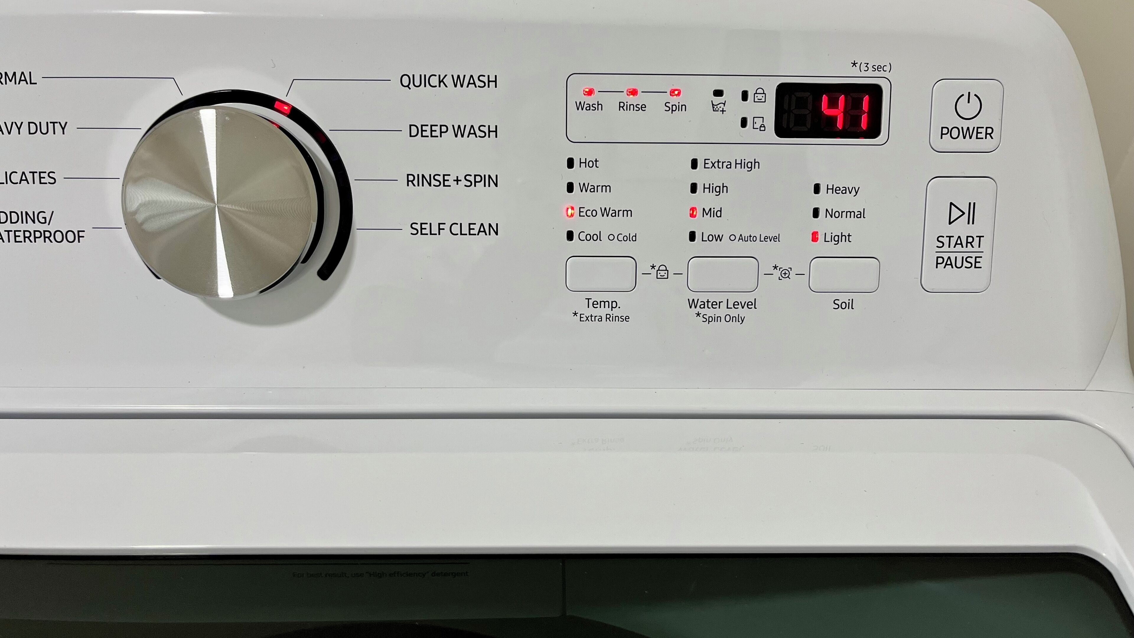 Panel de control de lavadora con diversas opciones de lavado y pantalla digital.
