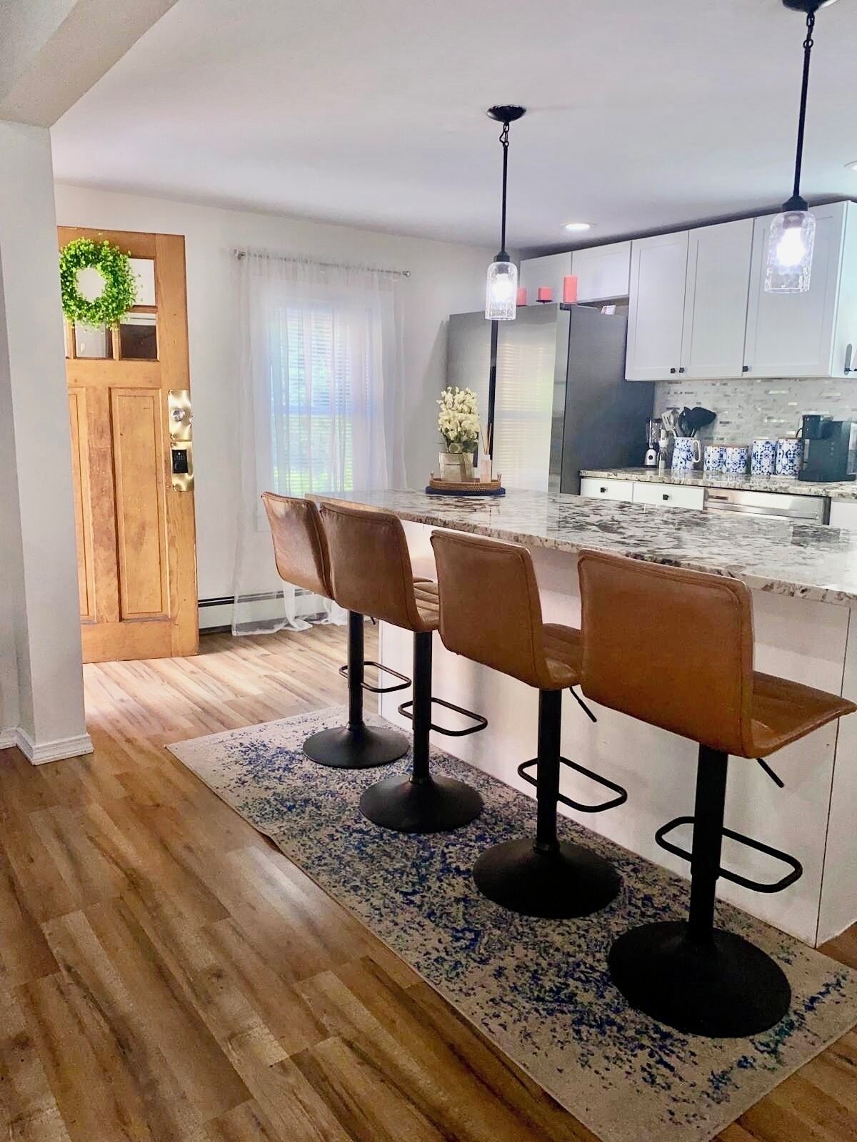 A modern kitchen with a central island, bar stools, and pendant lighting.