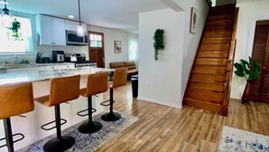 Une cuisine moderne dotée d’un îlot central, de tabourets de bar et d’un escalier en bois.