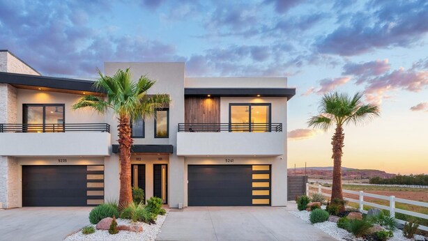 A modern two-story house with a garage, numbered 5235 and 102, and 101, with a white fence and palm trees in the driveway. - Desert Sands at Pecan Valley Resort  (Hurricane)