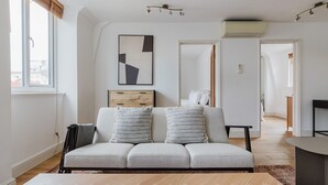 En moderne stue med en grå sofa, et træbord og et indrammet abstrakt billede.