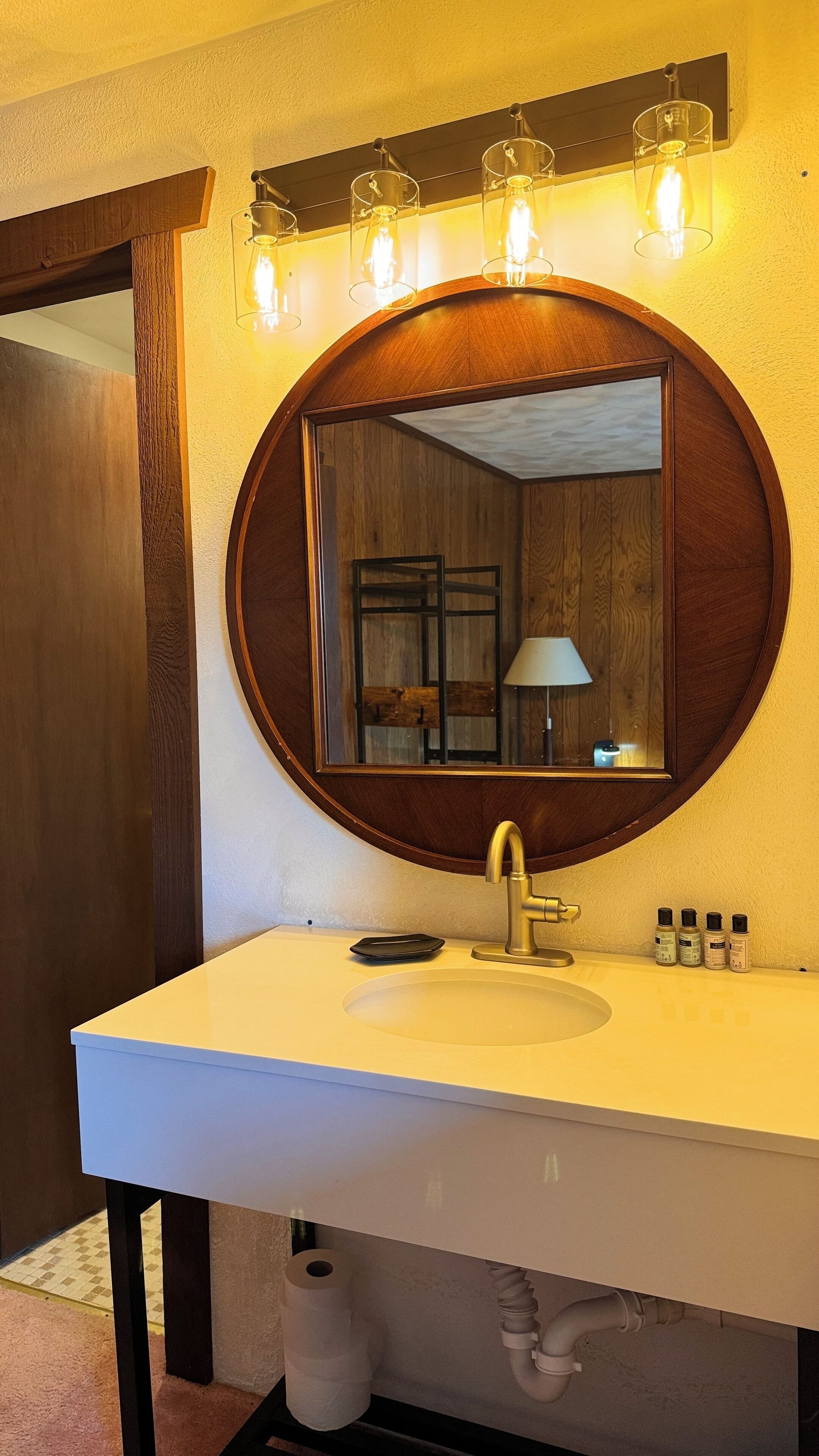 A bathroom with a round mirror, a white sink, and a towel rack.