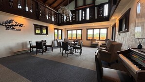 A spacious room with a piano, multiple seating areas, large windows, and a mountain view. - Davos Chalet (Upson)