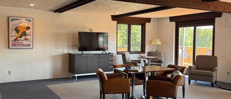 A modern living room with a TV, a dining table, and comfortable seating.