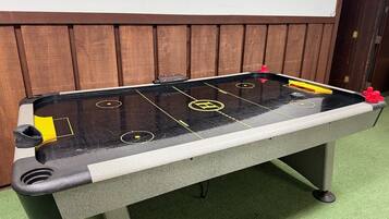 A foosball table with a black and white surface, yellow and red player figures, and a wooden backdrop.