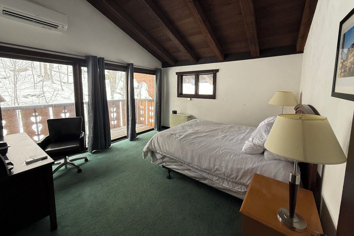 A hotel room with a bed, desk, chair, and two bedside lamps.