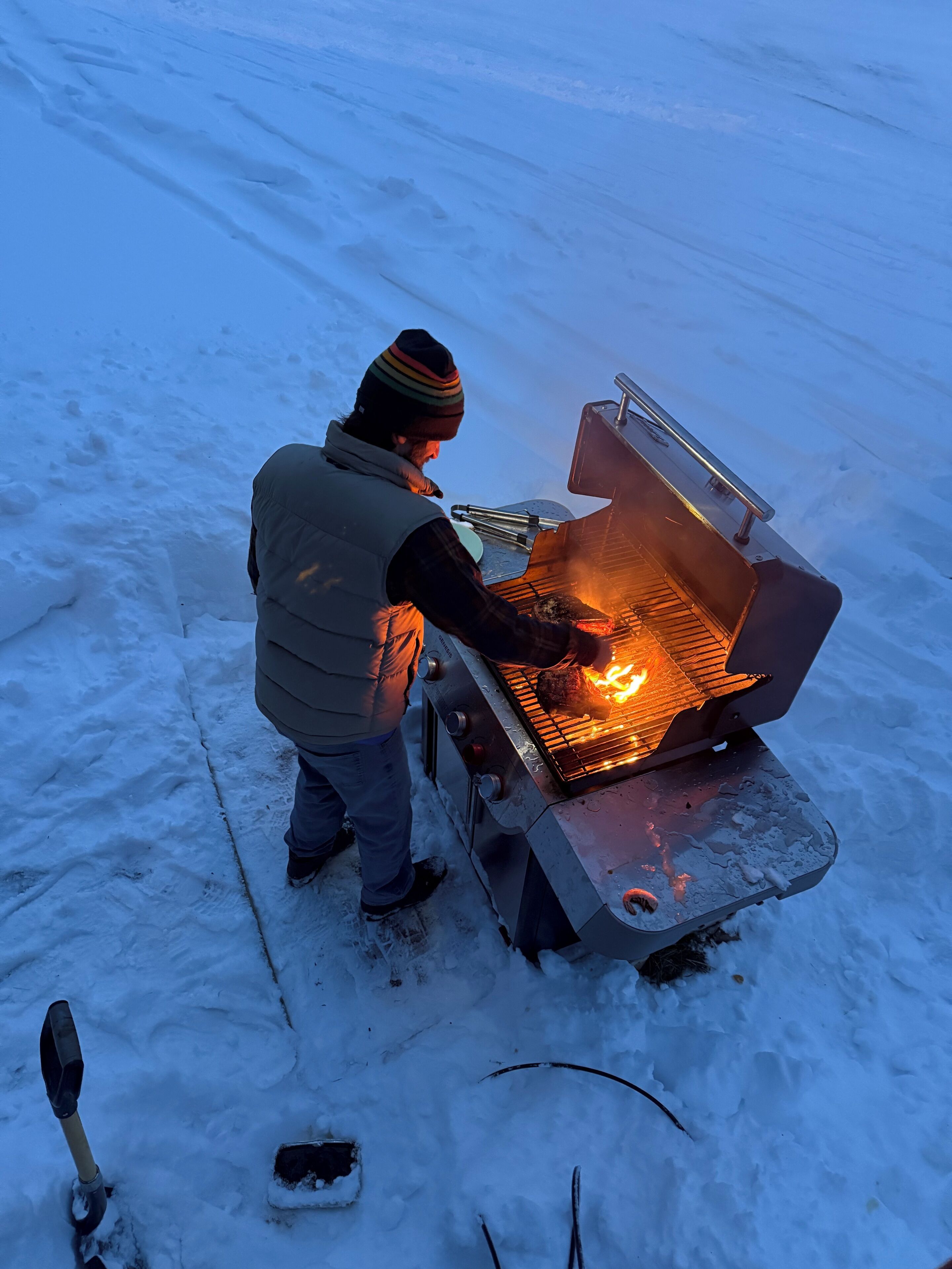 A person grilling outdoors in a snowy environment.