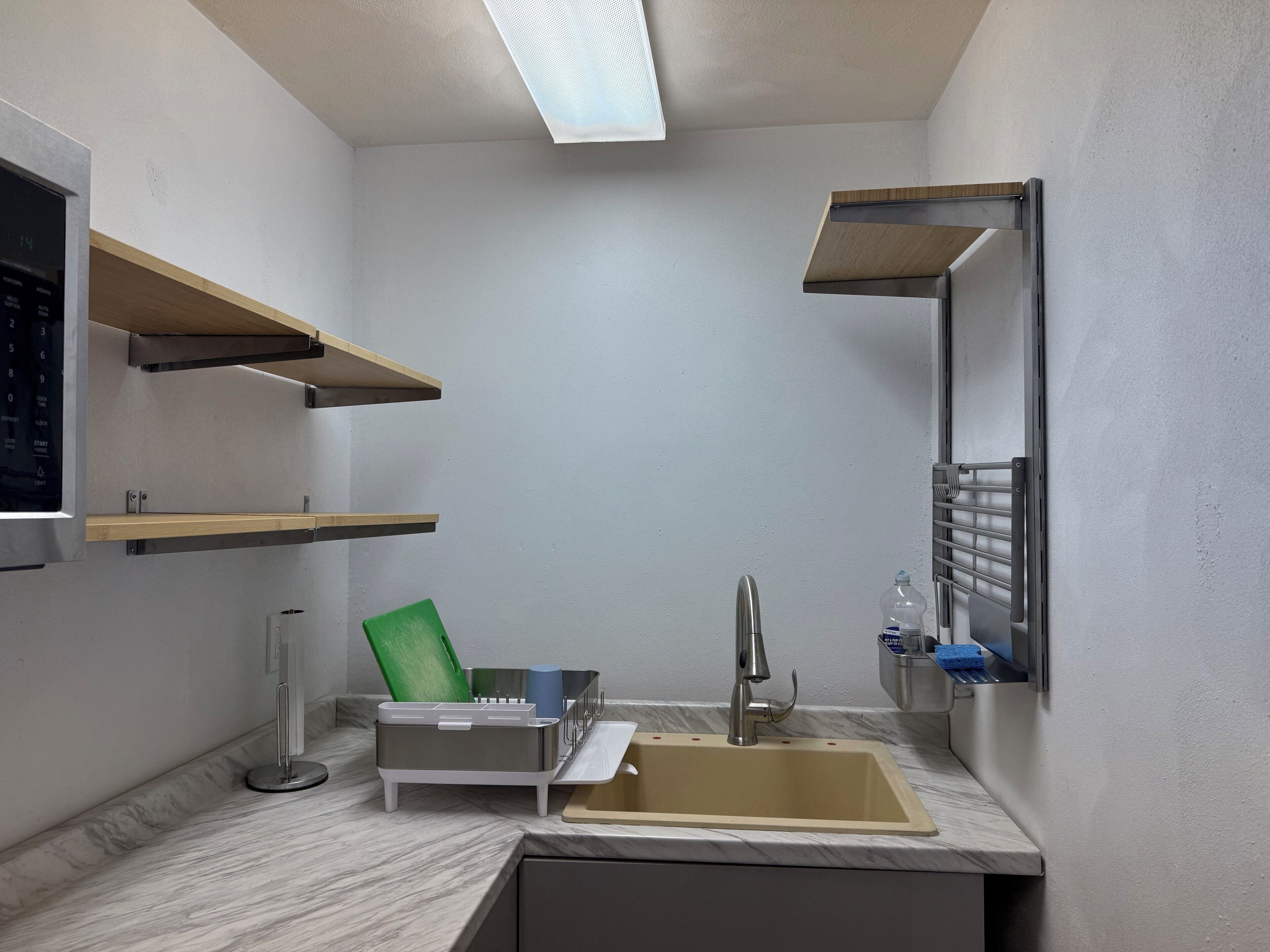 A compact bathroom with a sink, mirror, and shelves.