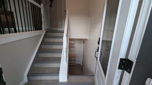A staircase with a white railing and a door with a black handle. - Peaceful and Inviting 4 Bedroom Bilevel House  (Red Deer)