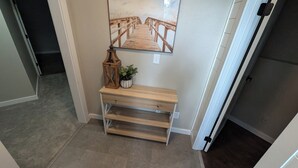 A hallway with a wooden console table, a potted plant, and a mirror reflecting a wooden deck. - Peaceful and Inviting 4 Bedroom Bilevel House  (Red Deer)