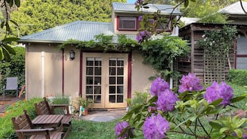 Enjoy a serene retreat in this charming house surrounded by lush gardens and a tree-lined backdrop.