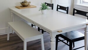 A dining area with a white table, black chairs, a wooden bench, a framed picture, and a door. - Walking distance to Wellspan York Hospital, York College. Comfortably sleeps 8. (York)