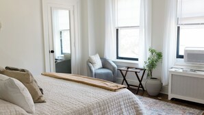 A bedroom with a bed, a chair, a small table, a plant, and a radiator. - Walking distance to Wellspan York Hospital, York College. Comfortably sleeps 8. (York)