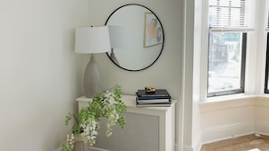 A room with a radiator, a lamp, a framed picture, and a window with blinds. - Walking distance to Wellspan York Hospital, York College. Comfortably sleeps 8. (York)