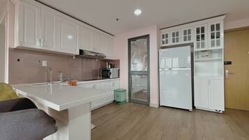 A modern kitchen with white cabinets, a stainless steel range hood, a microwave, and a refrigerator.