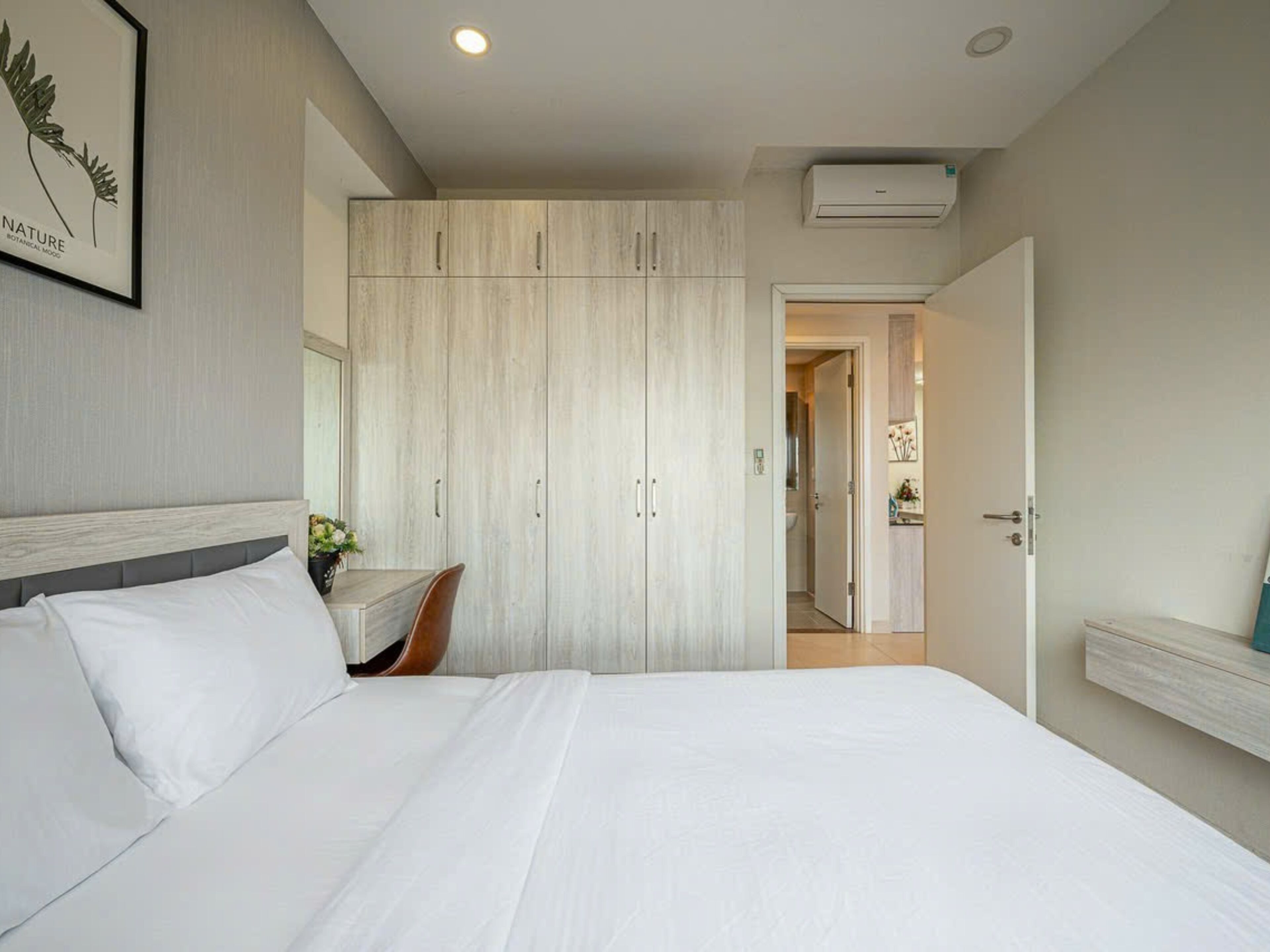 Une chambre à coucher avec un grand lit, une armoire, une table de chevet et un miroir.