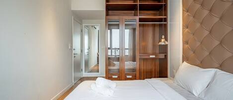 A bedroom with a bed, a wardrobe, and a view of a balcony.