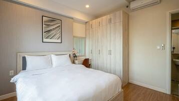 A bedroom with a large bed, wooden wardrobe, and an air conditioning unit.