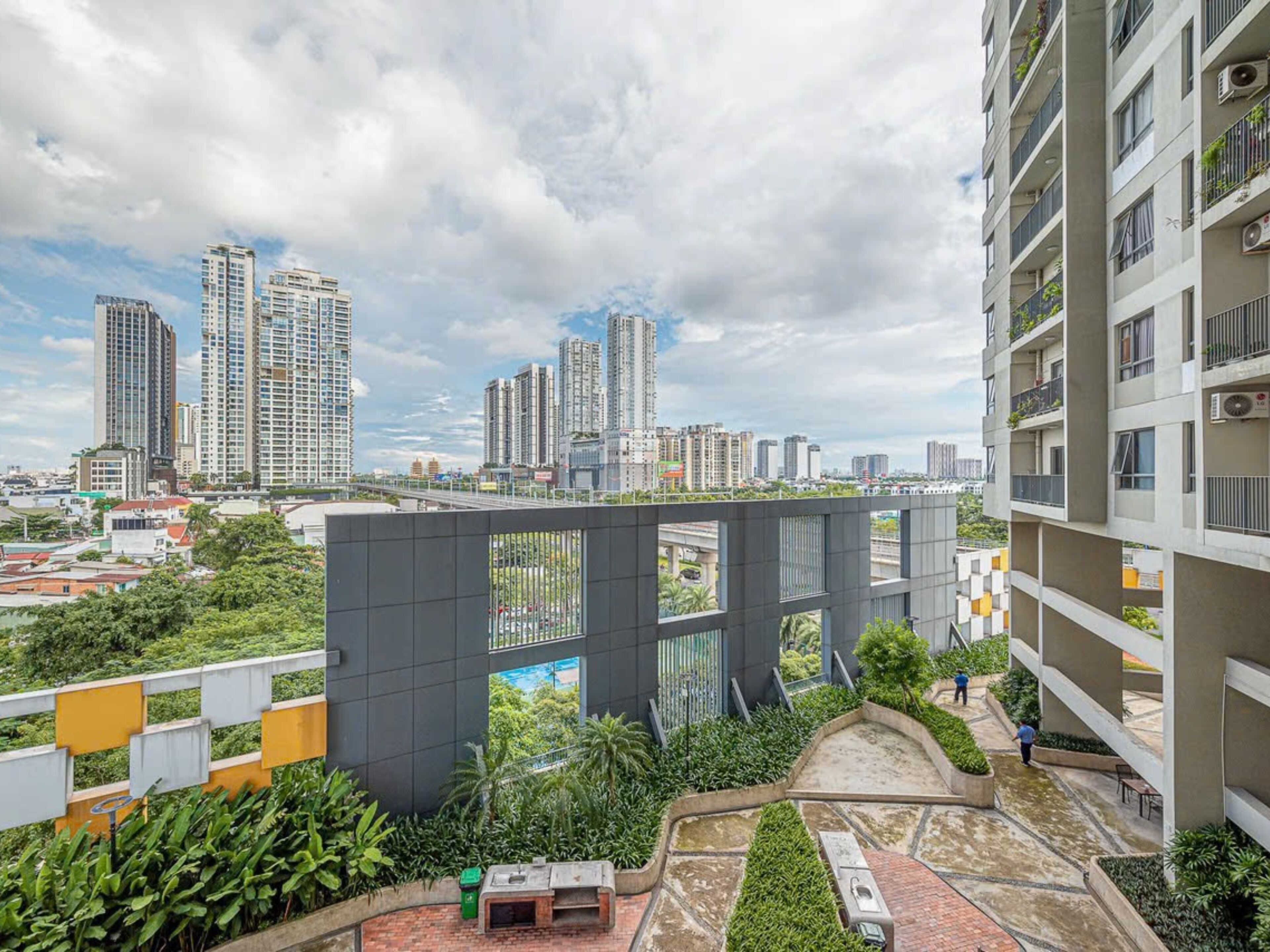 A high-rise residential building with a rooftop garden and a view of the city skyline.